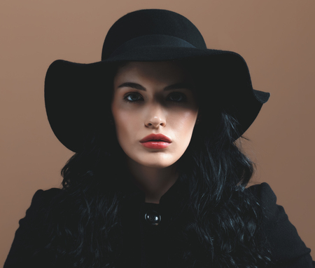 Beautiful young woman in a fashionable coat on a brown backgroundの写真素材