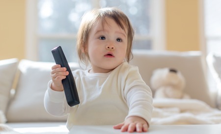 Little toddler boy with a TV remote controlの写真素材