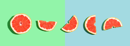 Halved fresh grapefruits on bright color background