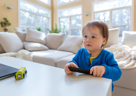 Little toddler boy with a TV remote controlの写真素材