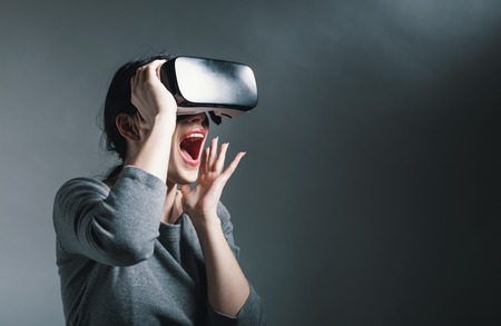 Young woman using a virtual reality headset on a gray backgroundの写真素材