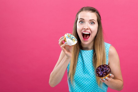 Young woman with donuts on a pink background