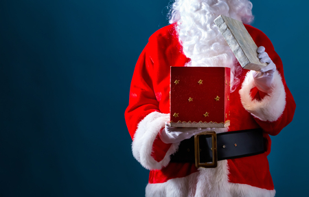 Santa opening a gift box on a dark blue backgroundの写真素材