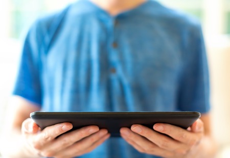 Young man with a tablet computer in a bright interior roomの写真素材