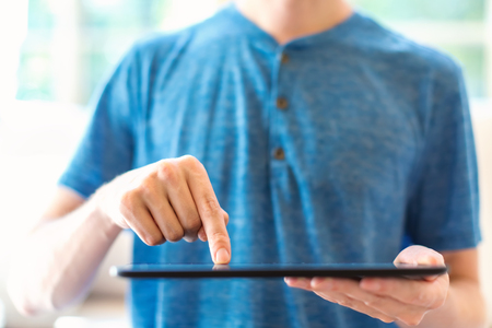 Young man with a tablet computer in a bright interior roomの写真素材
