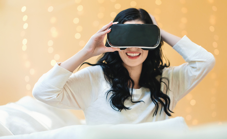 Young woman using a virtual reality headset on a shiny light backgroundの写真素材