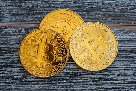 Gold bitcoin cryptocurrency coins on a wooden desk