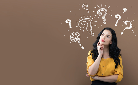 Question marks with young businesswoman in a thoughtful faceの写真素材