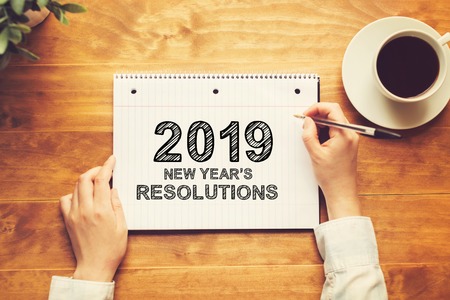 2019 New Years Resolutions with a person holding a pen on a wooden deskの写真素材