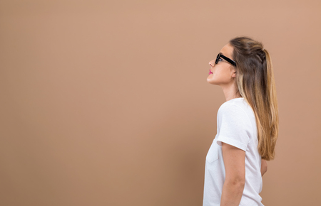 Young woman looking upwards on a brown backgroundの写真素材