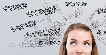 Stress theme with young woman looking upwards on a gray backgroundの写真素材