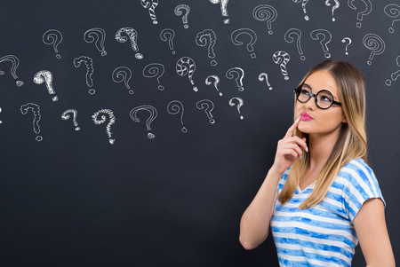 Small question marks with young woman in front of a blackboardの写真素材