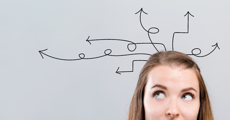 Idea arrows with young woman looking upwards on a gray backgroundの写真素材