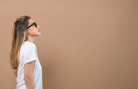Young woman looking upwards on a brown backgroundの写真素材