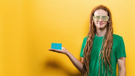 Happy man holding a retro cassette tape on a yellow backgroundの写真素材