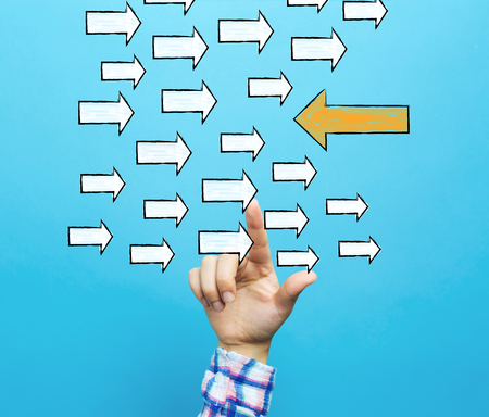 Arrow going in a opposite direction with hand on a blue backgroundの写真素材