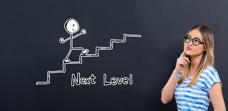 Next level concept with young woman in front of a blackboardの写真素材