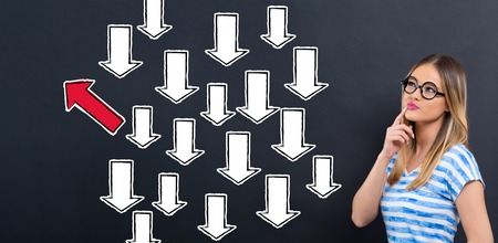 Arrow going in a different direction with young woman in front of a blackboard
