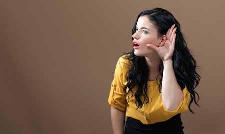 Young woman listening on a brown backgroundの写真素材
