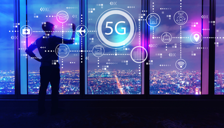 5G network with man writing on large windows high above a sprawling city at nightの写真素材