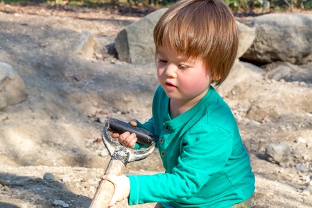 Toddler boy digging with a shovel outsideの写真素材