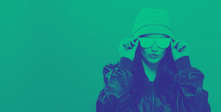 Fashionable woman with attitude in bomber jacket and sunglasses on a yellow background with duotone