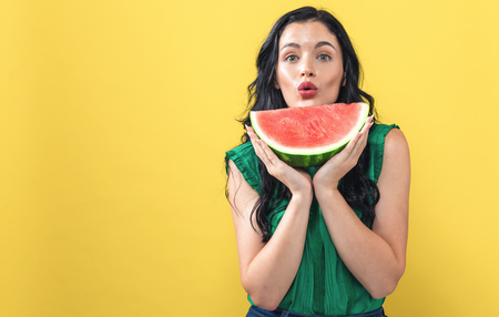 Young woman holding watermelon on a solid backgroundの写真素材
