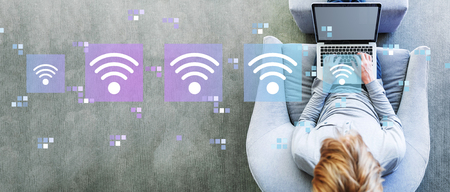 Wifi concept with man using a laptop in a modern gray chairの写真素材