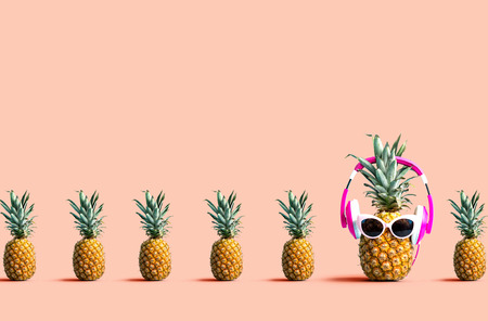 One out unique pineapple wearing headphones on a solid color backgroundの写真素材
