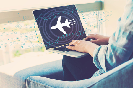 Airplane travel theme with woman using her laptop in her home officeの写真素材