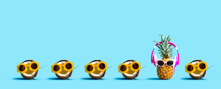 Pineapple and coconut wearing sunglasses on a solid color backgroundの写真素材