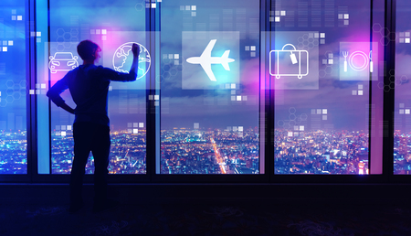 Airplane travel theme with man writing on large windows high above a sprawling city at nightの写真素材