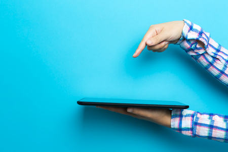 Person using a tablet computer device on a blue backgroundの写真素材