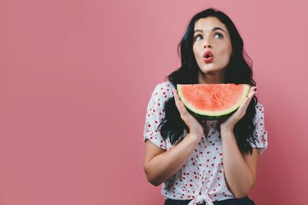 Young woman holding watermelon on a solid backgroundの写真素材