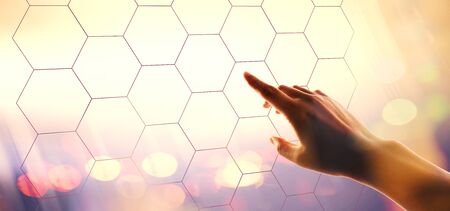 Hexagon grid with hand pressing a button on a technology screenの写真素材