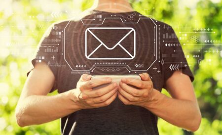 Email with young man holding his smartphone outsideの写真素材