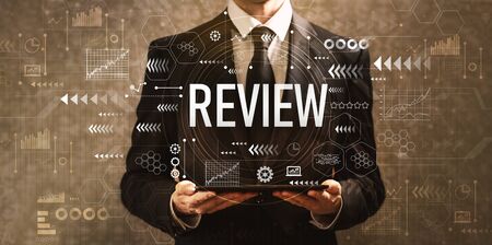 Review with businessman holding a tablet computer on a dark vintage backgroundの写真素材