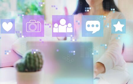 Social media with woman using her laptop in her home officeの写真素材