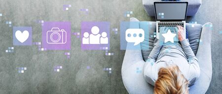 Social media with man using a laptop in a modern gray chairの写真素材