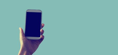 Person holding a white smartphone on a solid colored backgroundの写真素材