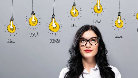 Idea light bulbs with young businesswoman in a thoughtful faceの写真素材