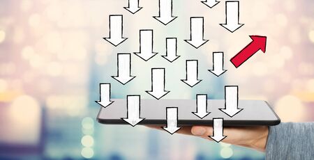 Arrow going in a different direction with man holding a tablet computerの写真素材