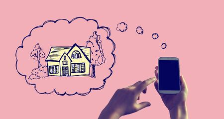 Dreaming of new home with person holding a white smartphoneの写真素材