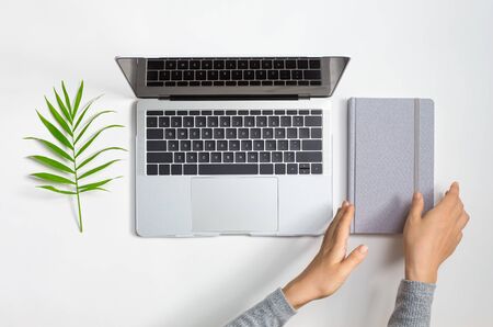 Person using a laptop computer with a notebookの写真素材