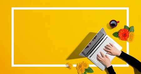 Person using a laptop computer with autumn flowers - overhead view