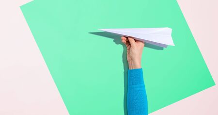 Person holding a paper airplane with hard shadowの写真素材