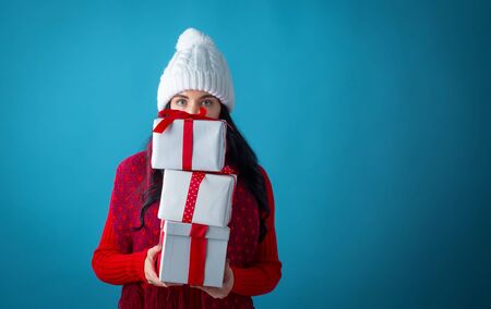 Young woman with gift boxes on a dark blue background