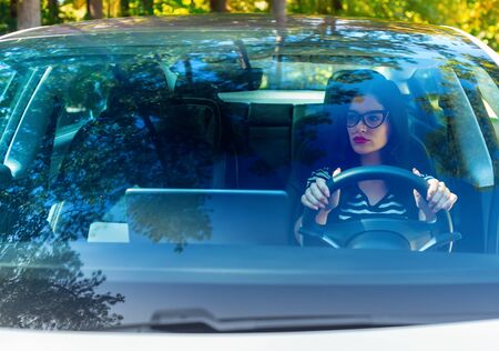 Woman in glasses driving a modern luxury car