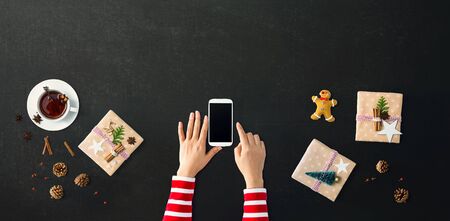 Christmas ornaments with person using a smartphone - overhead view