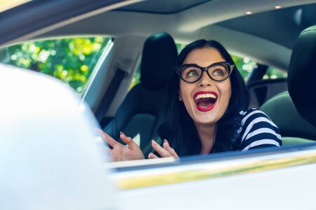 Woman in a self-driving autonomous electric vehicle with hands off the steering wheel